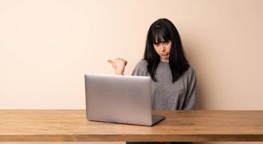 Dizüstü bilgisayarı ile çalışan genç bir kadın mutsuzdu ve yüzünü gösteriyordu.