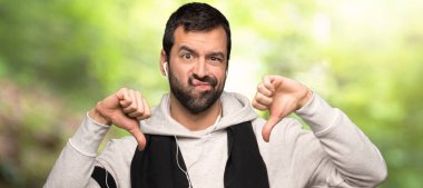 Spor adam bir parkta her iki eliyle başparmak aşağı gösteren