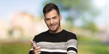 Yakışıklı adam ön işaret ve açık havada gülümseyen