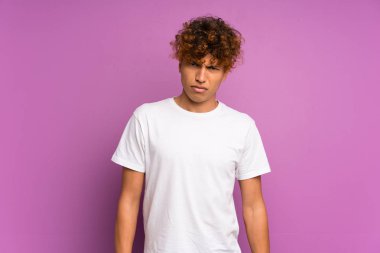 Hüzünlü ve depresif bir ifadeyle yalıtılmış mor duvarın üzerinde yaşayan genç bir Afro-Amerikan.