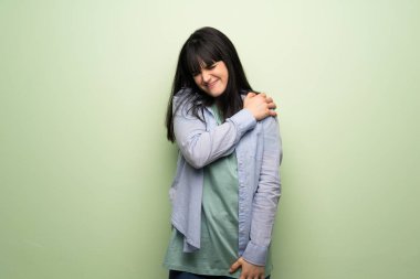 Yeşil duvarın ardında çabaladığı için omuz ağrısı çeken genç bir kadın.