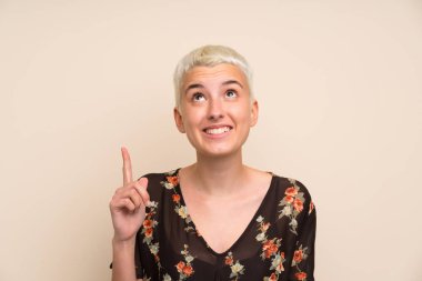 İzole edilmiş duvarın üzerinde işaret eden genç bir kadın. Harika bir fikir.