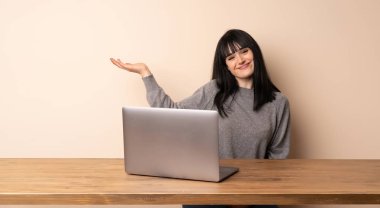 Dizüstü bilgisayarıyla çalışan genç bir kadın gülümseyerek bir fikir sunuyor.