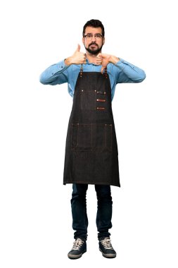 Apron ile adam tam uzunlukta çekim iyi-kötü işareti yapma. İzole beyaz arka plan üzerinde Evet veya değil arasında kararsız