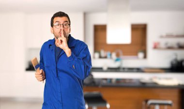 Ressam adam sessizlik jest gösteren bir işareti ağzına parmak koyarak evde