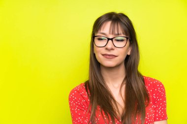 Yeşil duvarın üzerinde duran ve yan tarafa bakan genç bir kadın.