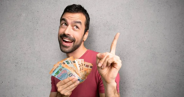 Adam büyük bir fikir işaret ve dokulu duvara bakarak çok para alarak