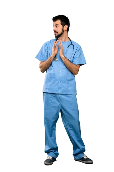孤立した白い背景の上に何かを企んでいる外科医医者の男の完全な長さのショット — ストック写真