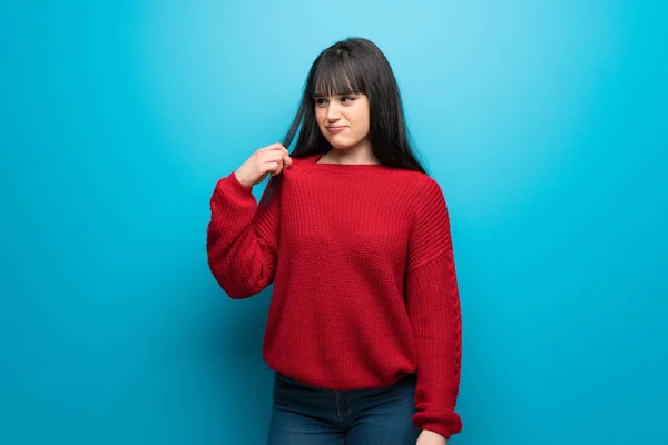 Woman with red sweater over blue wall with tired and sick expression