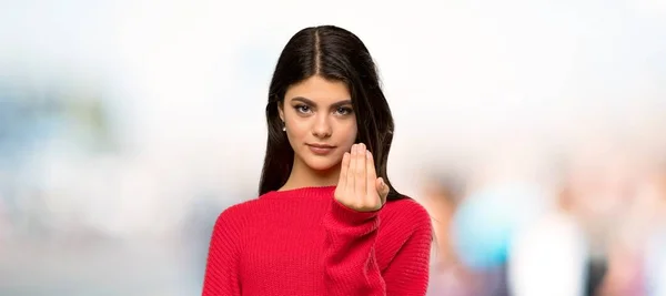 赤いセーターを持ったティーンエイジャーの女の子は手で来るように招待します あなたが屋外に来たことを幸せに — ストック写真