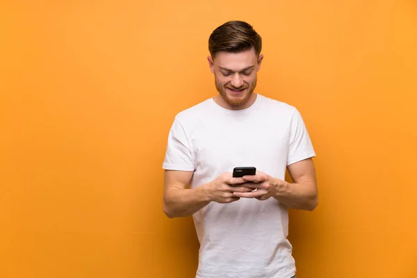 Ruda Człowiek Nad Brązową Ścianę Wysyłając Wiadomość Telefonem — Zdjęcie stockowe