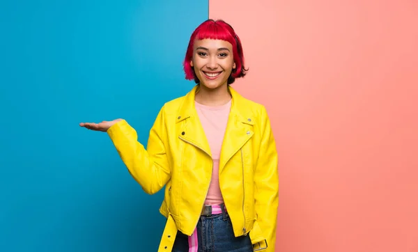 年轻的妇女与黄色夹克举行模仿空间想象在手掌插入广告 — 图库照片