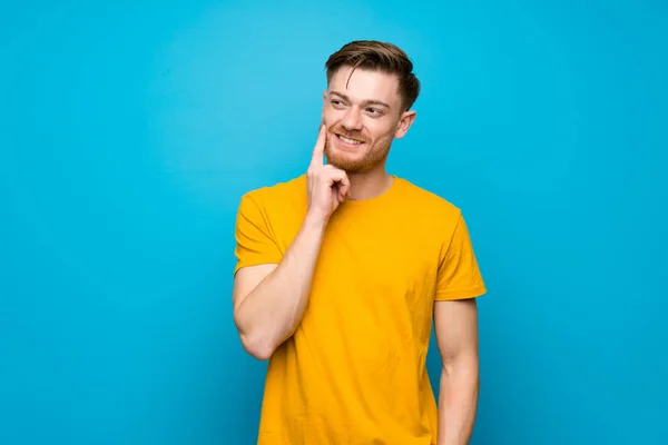 Mavi Duvar Üzerinde Redhead Adam Bakarken Bir Fikir Düşünüyor — Stok fotoğraf