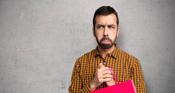 Dokulu duvar üzerinde üzücü ve depresif ifade ile alışveriş çantaları ile adam