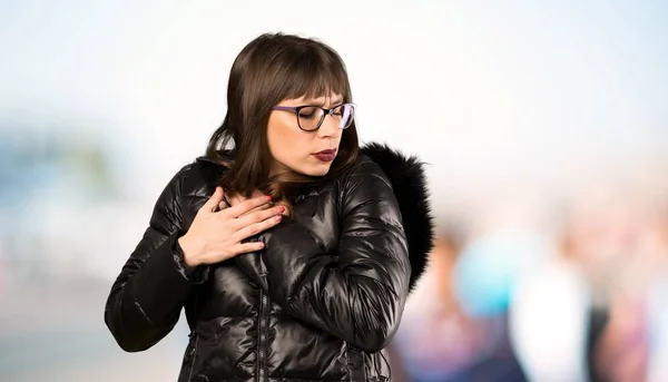 Woman with glasses having a pain in the heart at outdoors