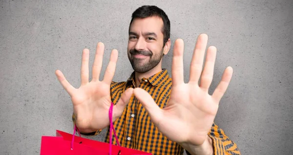 Hombre Con Bolsas Compras Contando Diez Con Dedos Sobre Pared —  Fotos de Stock