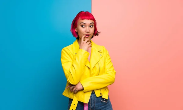 Young woman with yellow jacket having doubts while looking up
