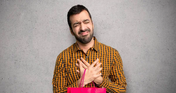 Dokulu duvar üzerinde kalp ağrısı olan alışveriş çantaları ile adam