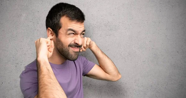 Yakışıklı adam dokulu duvar üzerinde eller ile her iki kulakları kaplayan