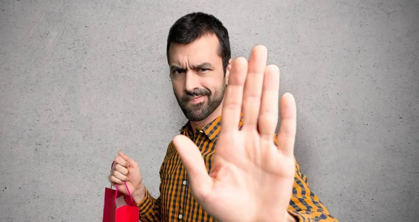 Adam alışveriş torbaları ile doku duvar üzerinde yanlış düşünüyor bir durum inkar durdurmak jest yapma