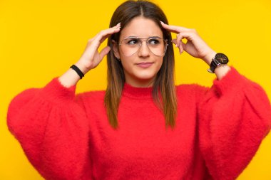 İzole sarı duvar üzerinde genç kadın mutsuz ve bir şey ile sinirli. Negatif yüz ifadesi