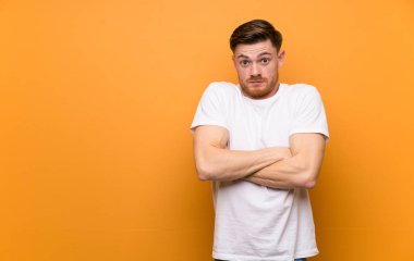 Omuzları kaldırırken şüphe jesti yapan kahverengi duvarın üzerinde kızıl saçlı adam