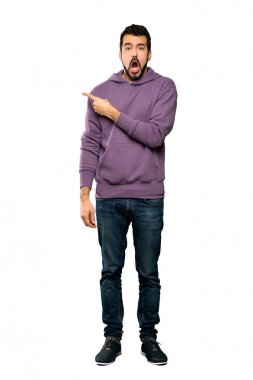 Sweatshirt ile yakışıklı adam tam uzunlukta çekim sürpriz ve izole beyaz arka plan üzerinde yan işaret