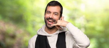 Spor yapan adam telefon hareketi yapıyor. Bir parkta bana geri çağrı işareti