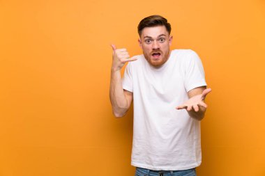 Kahverengi duvar üzerinde Redhead adam telefon jest yapma ve şüphe