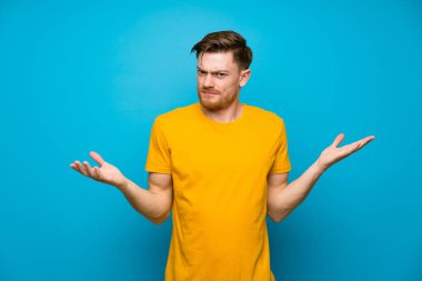 Mavi duvar üzerinde Redhead adam bir şey anlamak için mutsuz