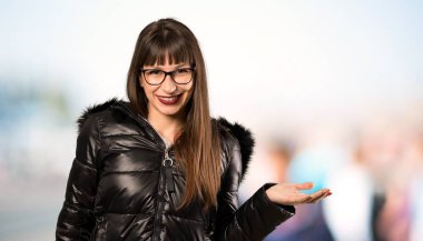 Açık havada bir reklam eklemek için avuç içinde boşaltmak hayali tutan gözlük kadın