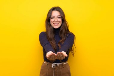 Bir reklam eklemek için palmiye üzerinde izole sarı duvar tutan boşaltmak hayali üzerinde genç kız