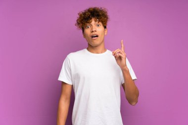 Genç Afro-Amerikalı adam, izole edilmiş mor duvarın üzerinde parmağını kaldıran bir fikir düşünüyor.