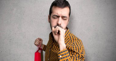 Alışveriş çantaları ile adam öksürük ile acı ve dokulu duvar üzerinde kötü hissediyorum