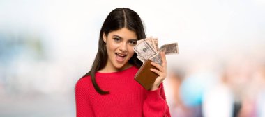 Açık havada bir cüzdan tutan kırmızı kazak ile genç kız