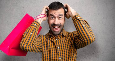 Dokuma duvar üzerinde migren var çünkü alışveriş çantaları ile adam kafasına el alır