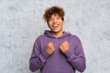 Genç Afro-Amerikan erkeği Grunge Duvarı 'nın ardında zaferi kutluyor.