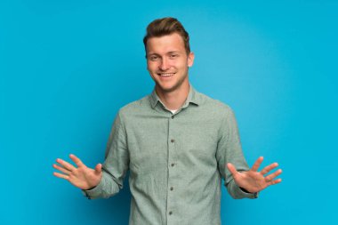 Sarışın adam üzerinde izole mavi duvar gülümseyen