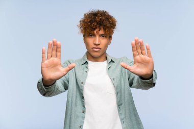 Genç Afro-Amerikan adam, mavi duvarın ötesinde durup jest yapıyor ve hayal kırıklığına uğruyor.