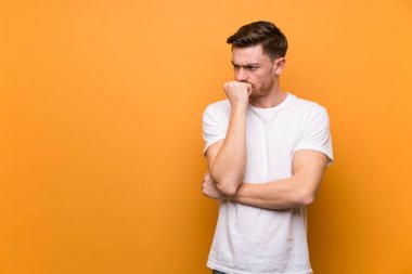 Kahverengi duvarın üzerinde kızıl saçlı adamın şüpheleri var.