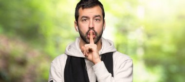 Bir parkta ağzına parmak koyarak sessizlik jest bir işareti gösteren spor adam