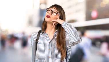 Gözlüklü kadın telefon hareketi yapıyor. Açık havada bana geri arama işareti