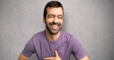 Dokulu duvar üzerinde göğsüne eller koyarak çok gülümseyen yakışıklı adam