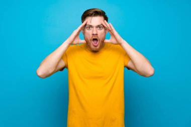 Sürpriz ifade ile mavi duvar üzerinde Redhead adam