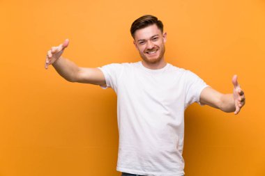 Kahverengi duvar üzerinde Redhead adam sunan ve el ile gelmek için davet