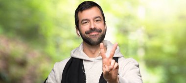 Spor adam gülümseyen ve bir parkta zafer işareti gösteren