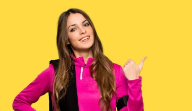 İzole sarı arka plan üzerinde bir ürün sunmak için yan işaret genç spor kadın