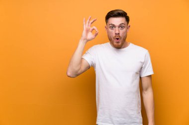 Kahverengi duvar üzerinde Redhead adam şaşırttı ve ok işareti gösteren