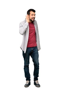 Tam uzunlukta kadeh bir şey izole beyaz arka plan üzerinde kulak el koyarak dinleme sakallı yakışıklı adam