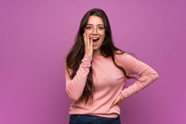 Genç kız sürpriz ve şok yüz ifadesi ile mor duvar üzerinde